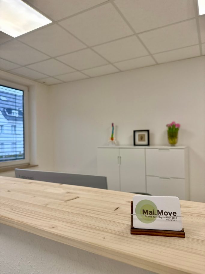 Minimalist Empfangsbereich mit hellem Holztresen, Pflanzen und dekorativem Wandregal.